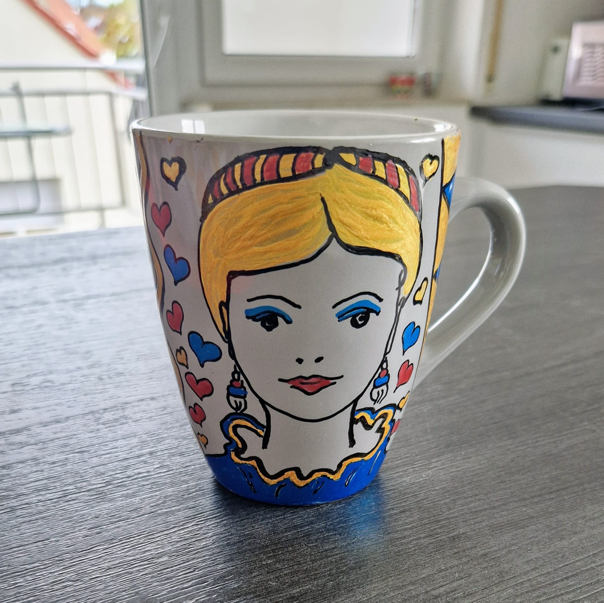 Graue Tasse bemalt mit Frauengesicht und Ornamenten